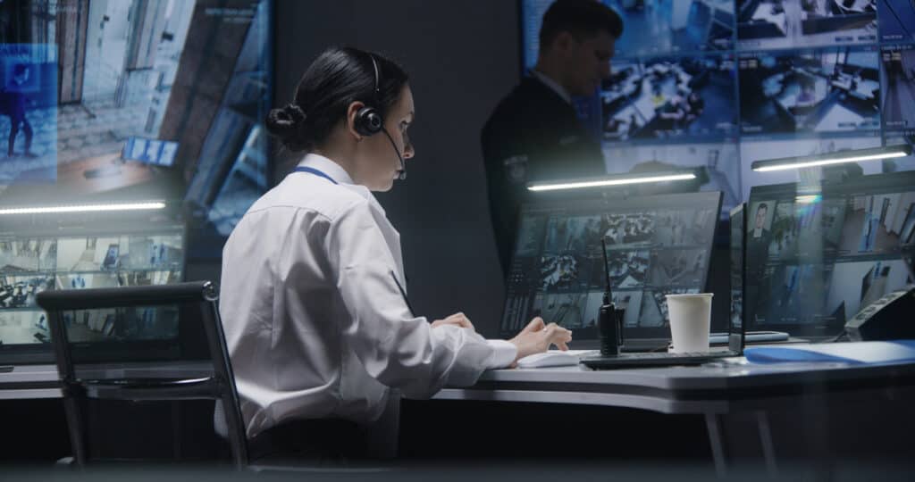 Female corporate security officer works on computer with CCTV cameras footage